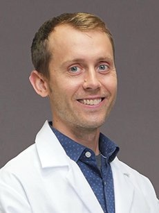 Epileptologist John Bunka, DO, smiles in a white coat.