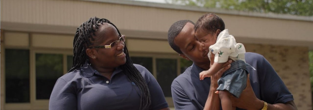 Photo of father and mother holding her baby.