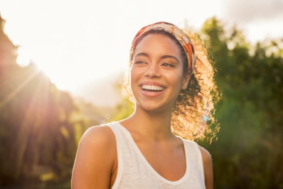 Photo of a young woman smiling outdoors.