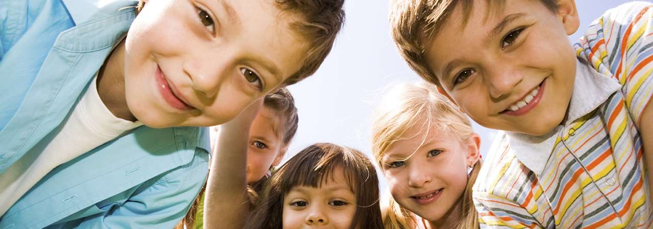 Photo of children outside, smiling.