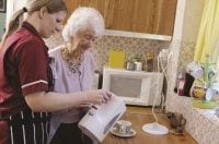 Staff member helping patient at the patient's home. 