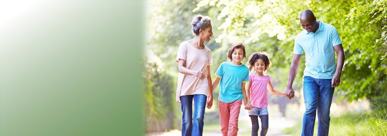 A happy family walking through a park.