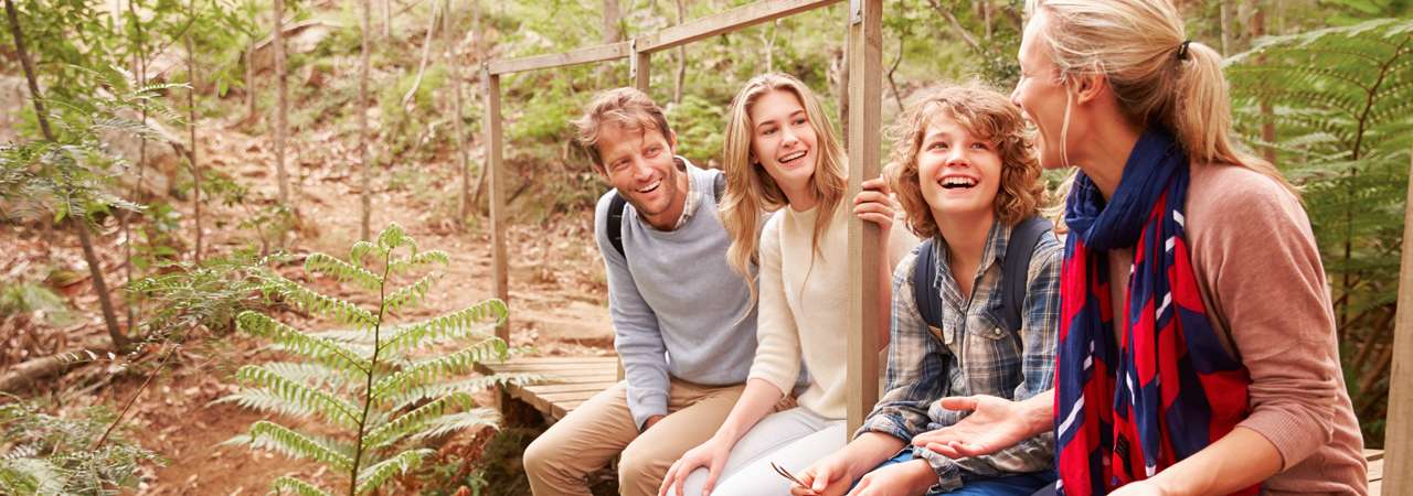 Photo of a family sitting in the forest talking.