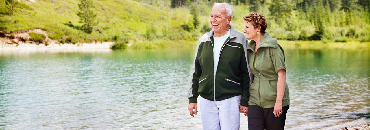 Photo of a woman on a man's back near a lake.