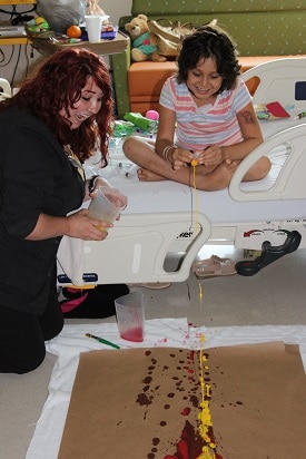 Photo of art therapist playing with paint with a young patient.