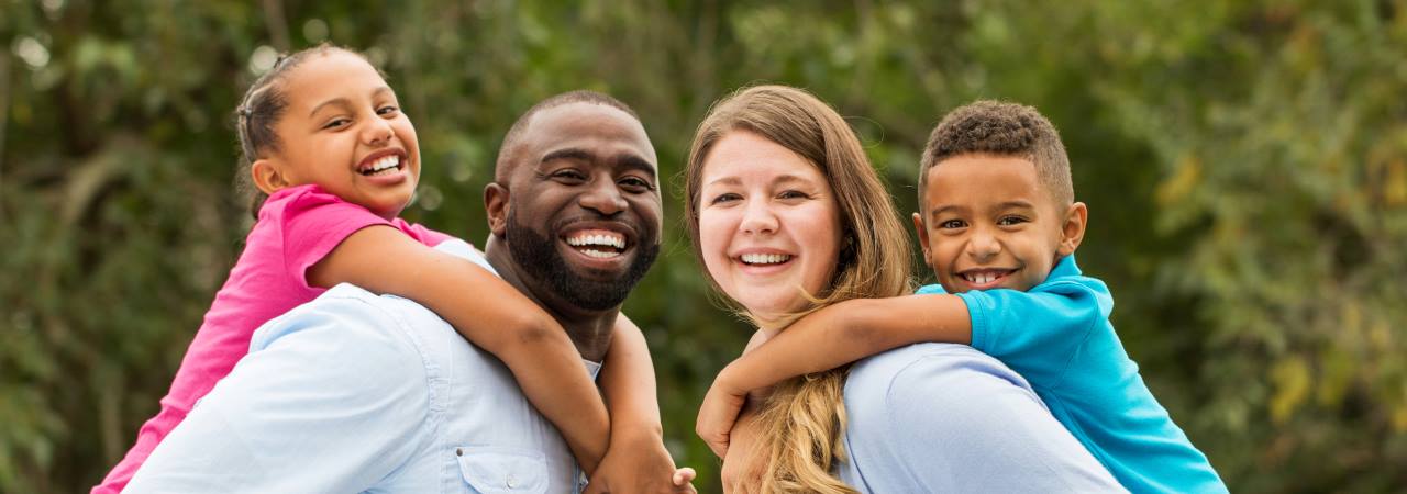 Photo of mother and father with kids on their backs.