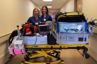 Two transport nurses stand in front of transport isolette