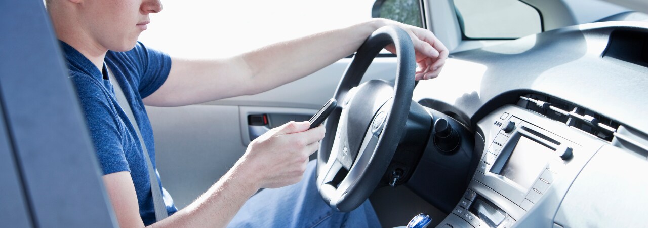 Photo of person on cell phone while driving.