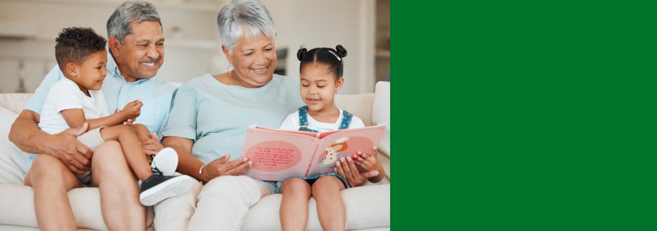 Photo of elderly couple reading to grandchildren.